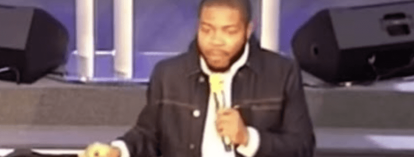 Man speaking with microphone on stage.